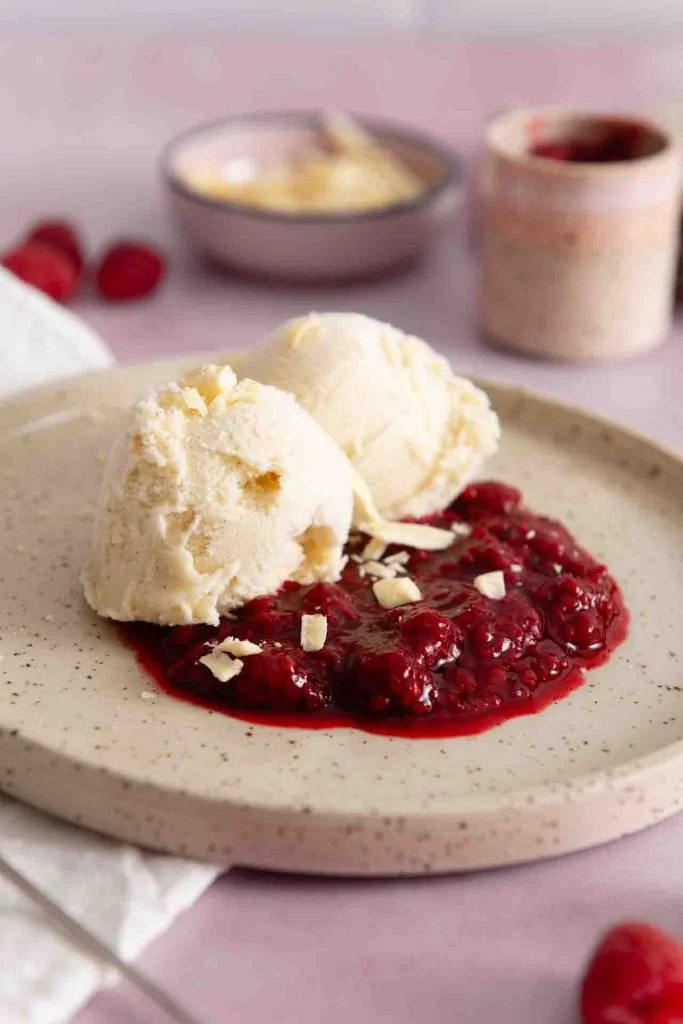 Ein Teller Vanilleeis auf heißen Himbeeren.