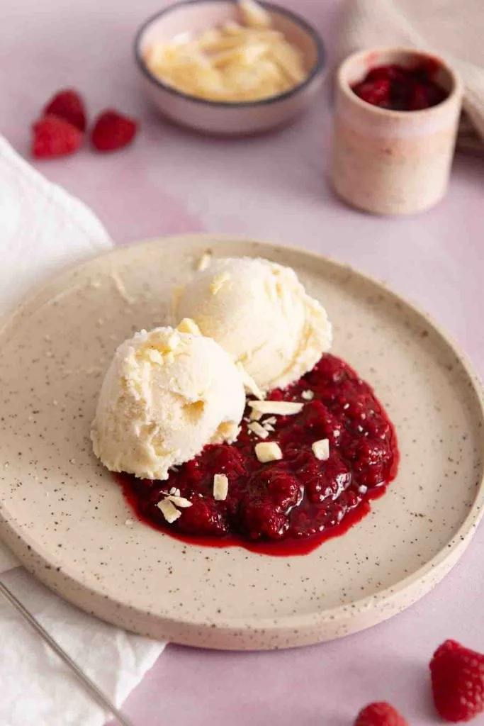 Ein Vanilleeis mit heißen Himbeeren auf dem Tisch.