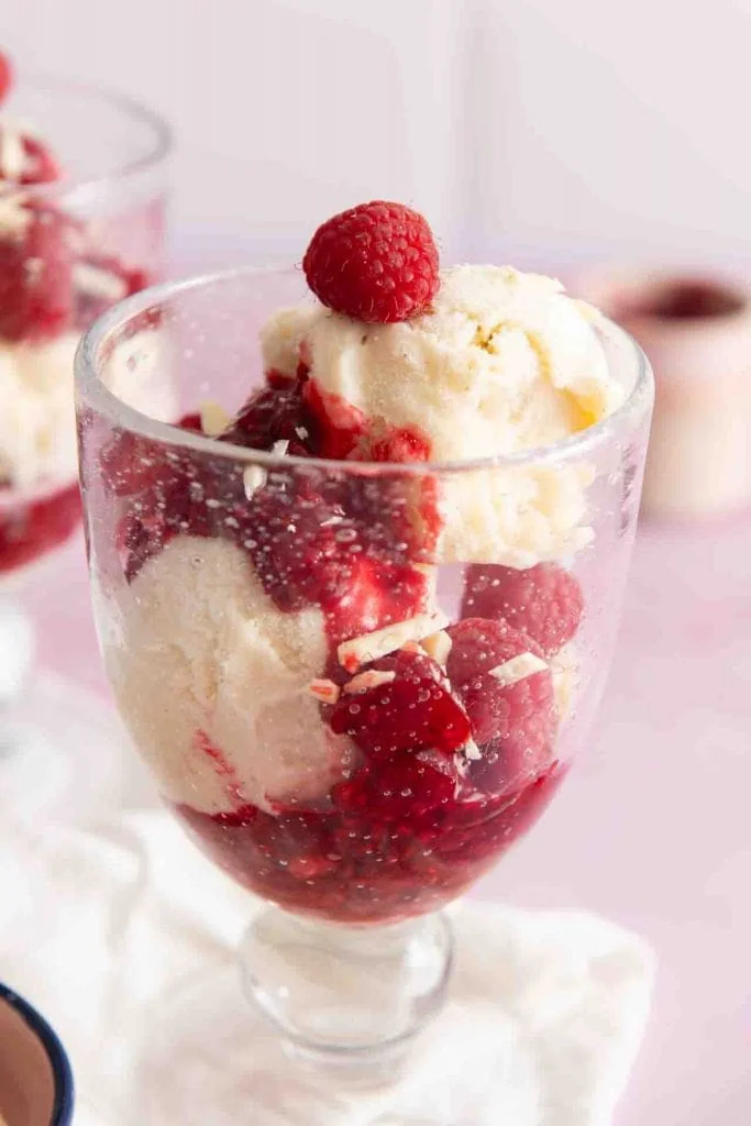 Ein Eisbecher mit einer Himbeere auf dem Eis.