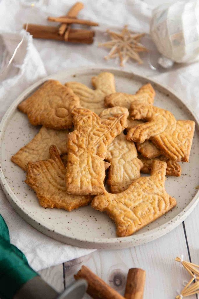 Ein paar Spekulatius liegen auf einem Teller. Der erste sieht aus wie ein Nikolaus.