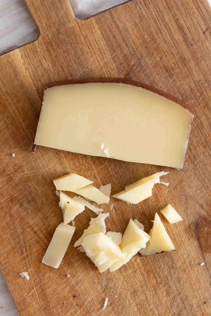 Ein Stück Pecorino mit klassischer schwarzer Wachsrinde ist zu seen sowie einige mundgerechte Stücke davon.