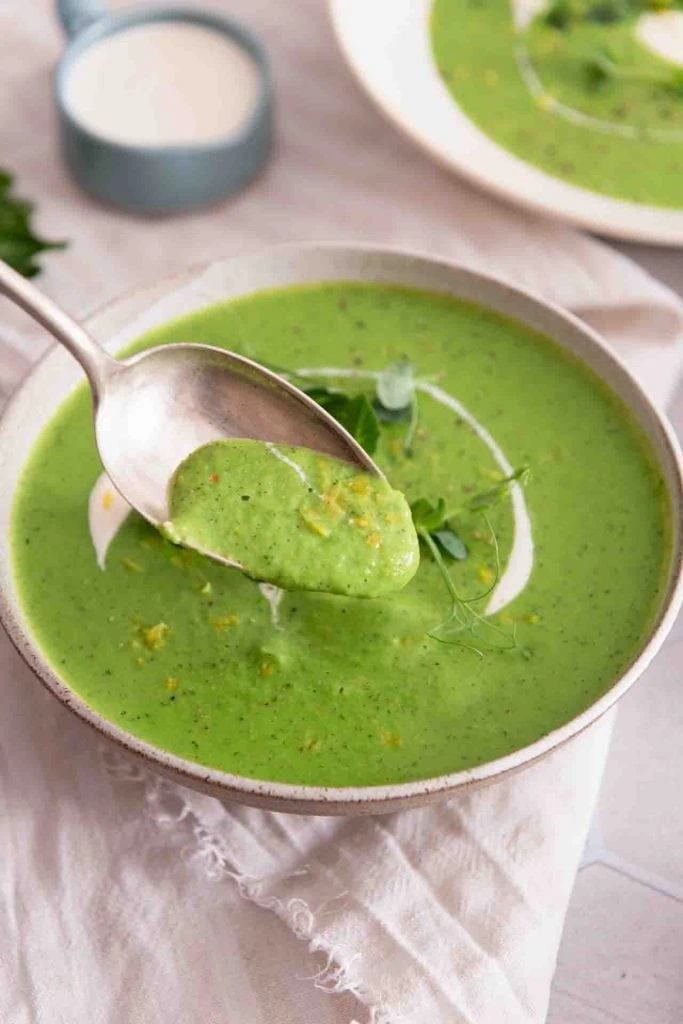 Ein Löffel nimmt etwas grüne Suppe aus.