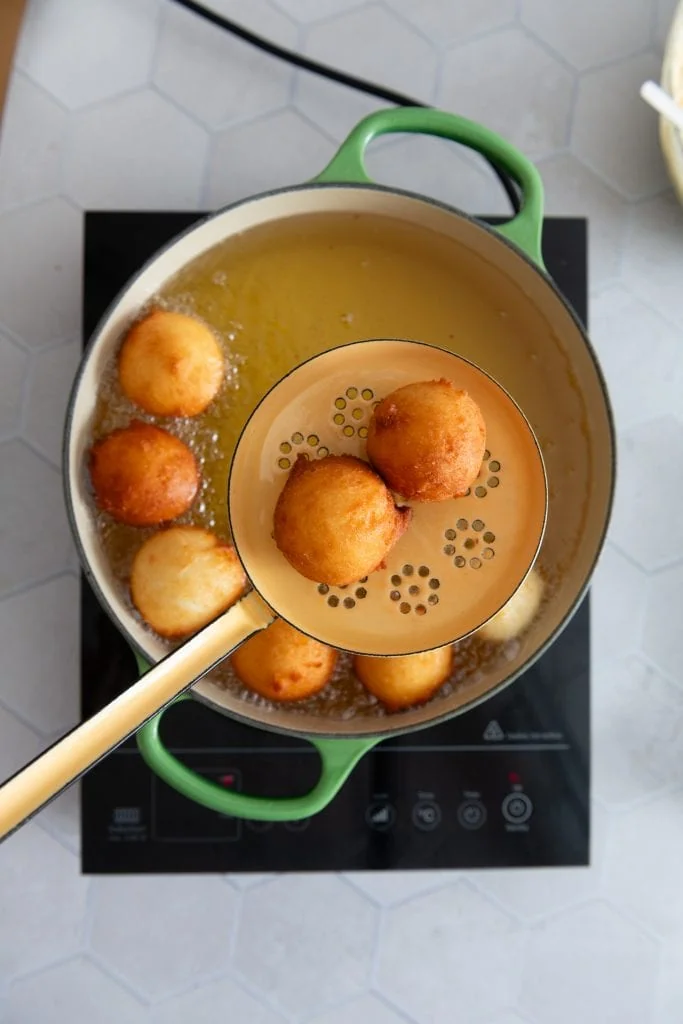 Die fertigen Quarkbällchen werden mit einer Schaumkelle aus dem heißen Öl gehoben.