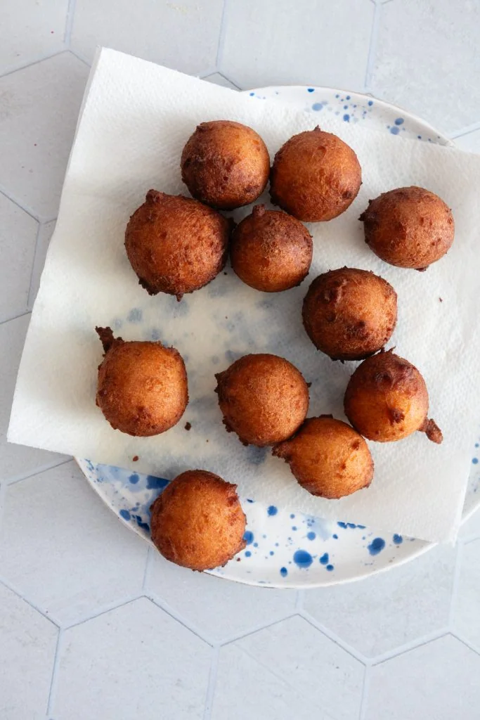 Die goldbraun gebackenen Quarkbällchen tropfen auf einem Teller mit Küchenrolle daraus ab.