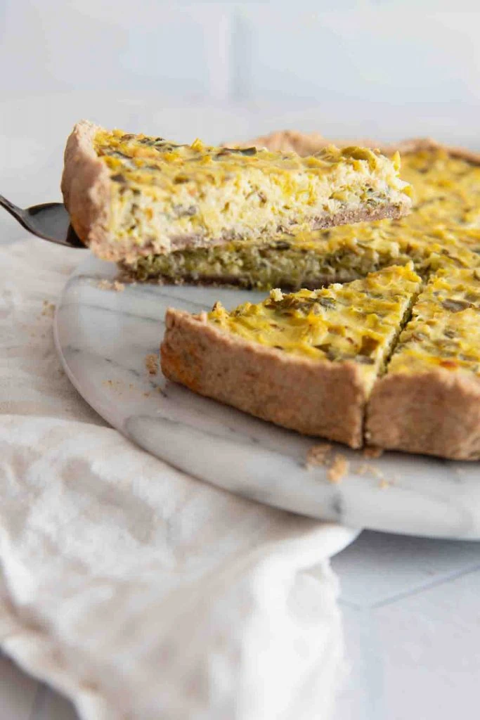 Ein Stück wird mit der Kuchengabel aus der Quiche geholt.