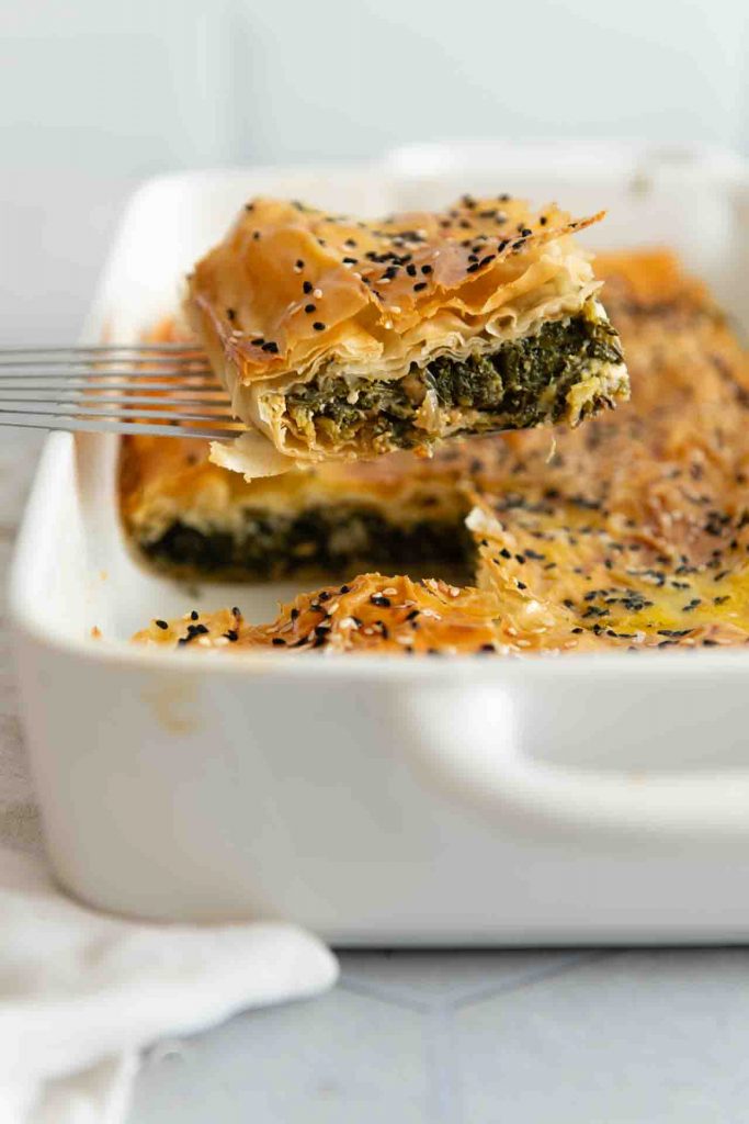 Ein Stück von dem griechischem Auflauf wird mit einem Pfannenwender hochgehoben.