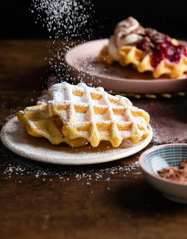 Puderzucker wird auf die Waffeln gestreut.