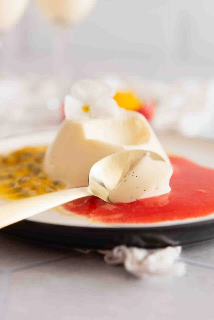 Ein Löffel nimmt etwas von dem Panna Cotta auf.