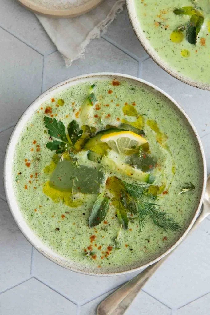 Auf der Gurkensuppe sieht man Zitronen und Kräuter.