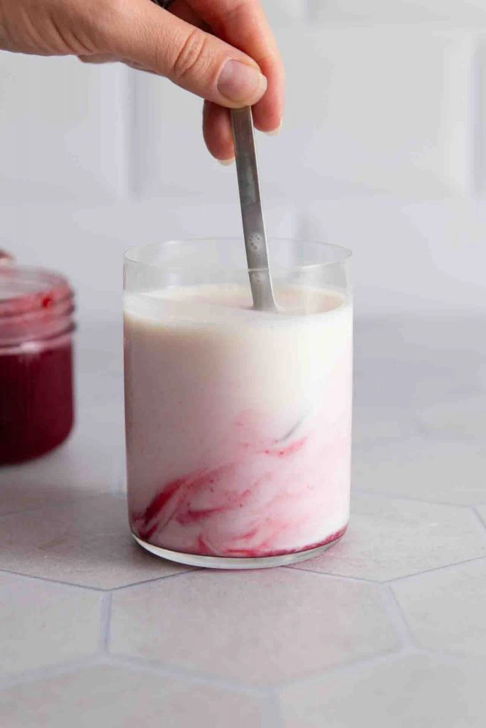 Etwas Himbeersirup wird in den Milchkefir eingerührt.