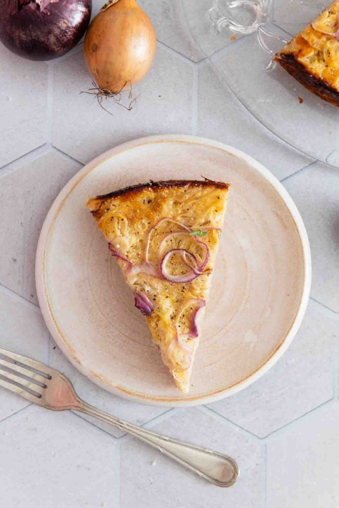 Ein Stück vom vegetarischen Zwiebelkuchen mit einer Gabel.