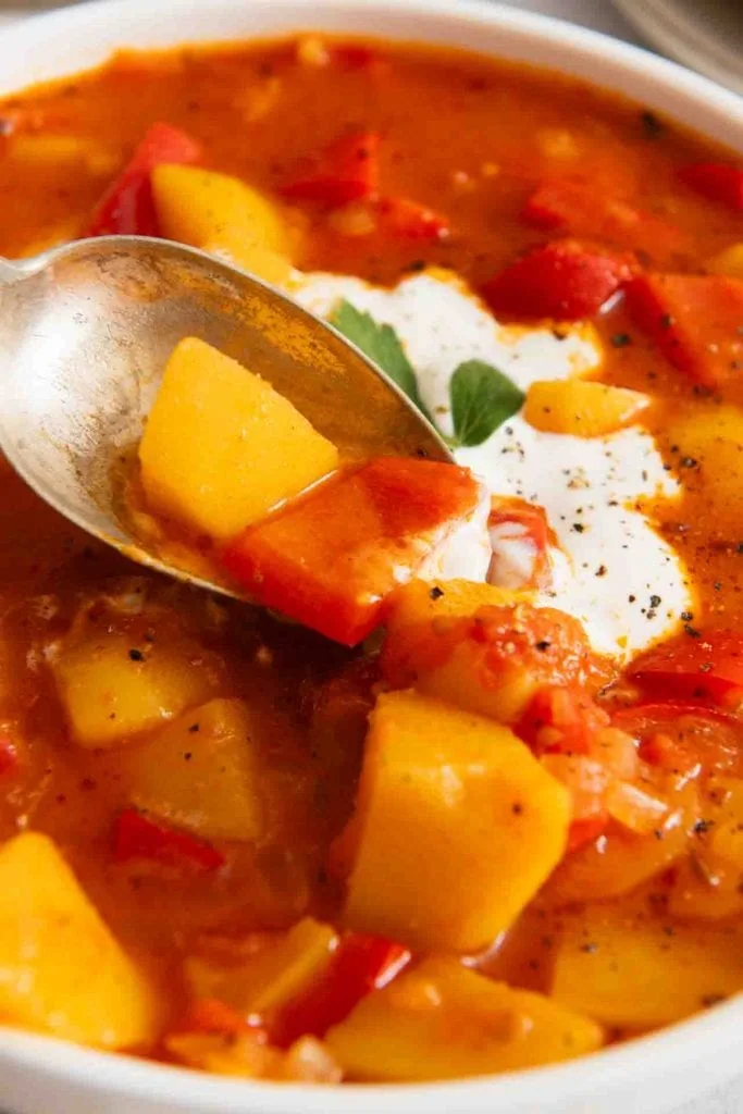 Ein Löffel nimmt etwas von dem Kartoffelgulasch vegetarisch auf.