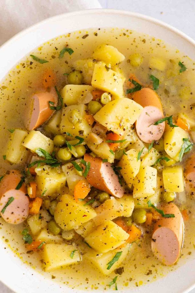 Der Erbseneintopf in der Nahaufnahme, man sieht Kartoffeln, Karotten und veggie Würstchen.