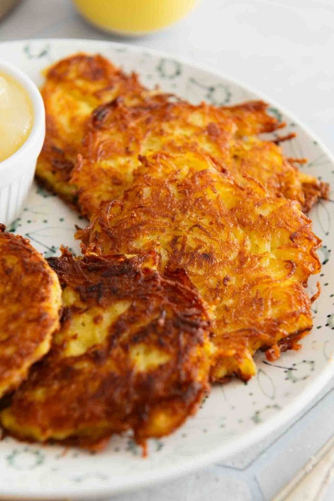 Ein paar Kartoffelpuffer neben Apfelmus auf einem Teller.