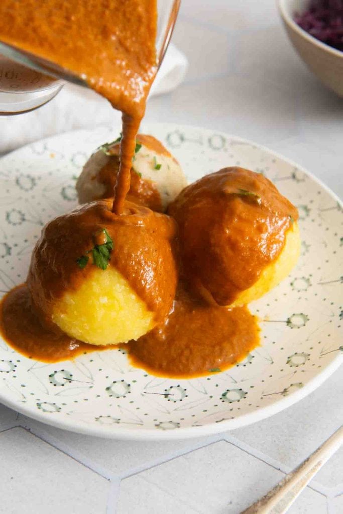 Über die Knödel wird die Sauce gekippt mit einer Sauciere.