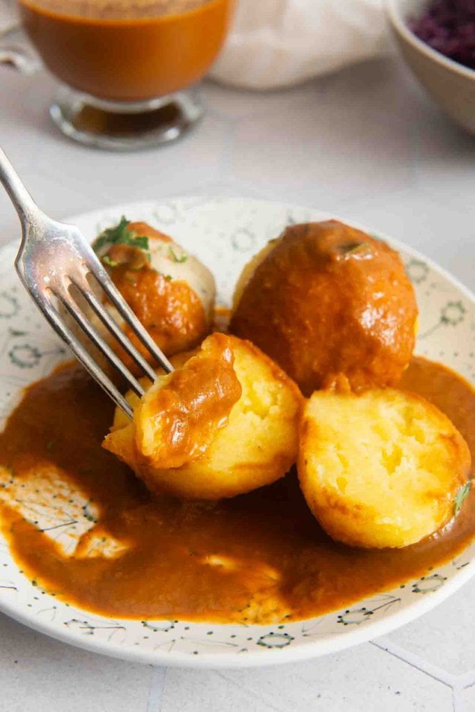 Eine Gabel nimmt etwas von dem Semmelknödel mit Blaukraut auf.